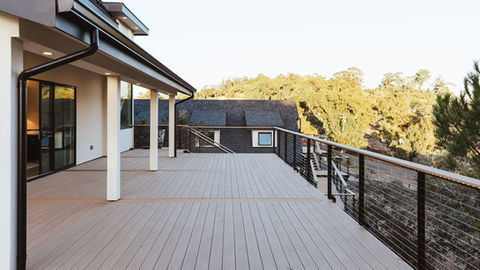 a deck with stairs leading up to a house with a black roof