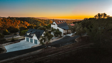 a large white house sits on top of a hill at sunset