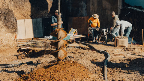 a man is using a cell phone while another man works on a table