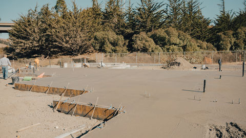 a construction site with a fence and trees in the background