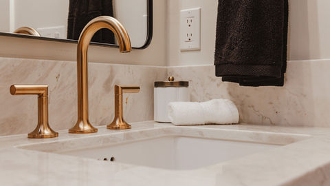 a bathroom sink with a brass faucet and a white towel