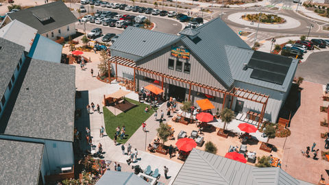 an aerial view of a large building, red umbrellas and tables