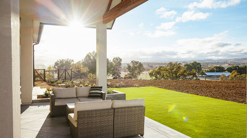 a patio with a couch and chairs with a view of a field