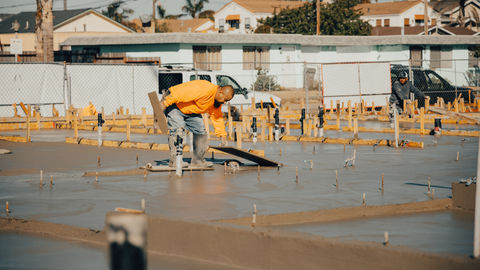 a man in an orange shirt is working on a concrete floor