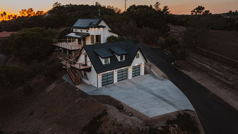 a white house with a black roof and black garage doors