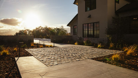a cobblestone driveway leads to a large house