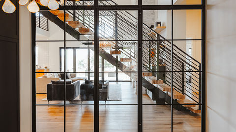 a view of a living room and stairs through a glass door