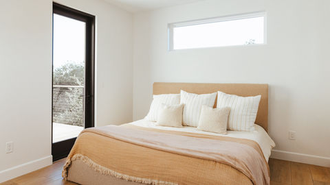 a bed with striped pillows and a tan headboard