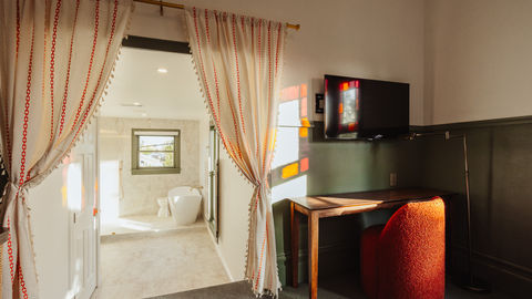 a room with a desk and a television on the wall