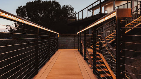 a wooden deck with a black railing and stairs