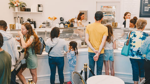 a group of people standing in front of a counter that says ice cream