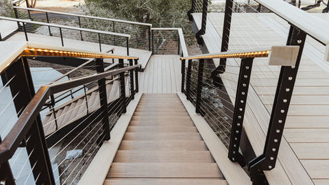a set of stairs leading up to a deck with a stainless steel railing