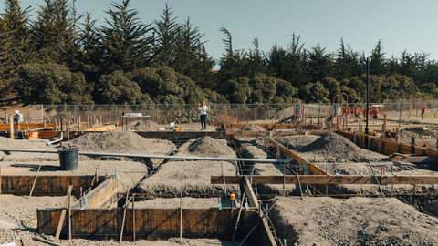 a woman in a white shirt stands on a construction site