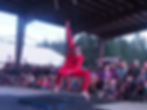 Charles in red performing in an outdoor shelter