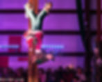 Charles as the Grinch in a winter performance, hanging upside down from fabric