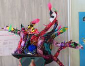 Colorful fabric sculpture with sunglasses, some text visible on a poster