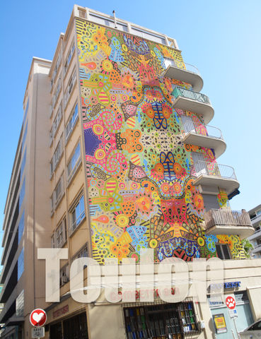 Colorful mural on the building with Toulouse text; street view in natural light
