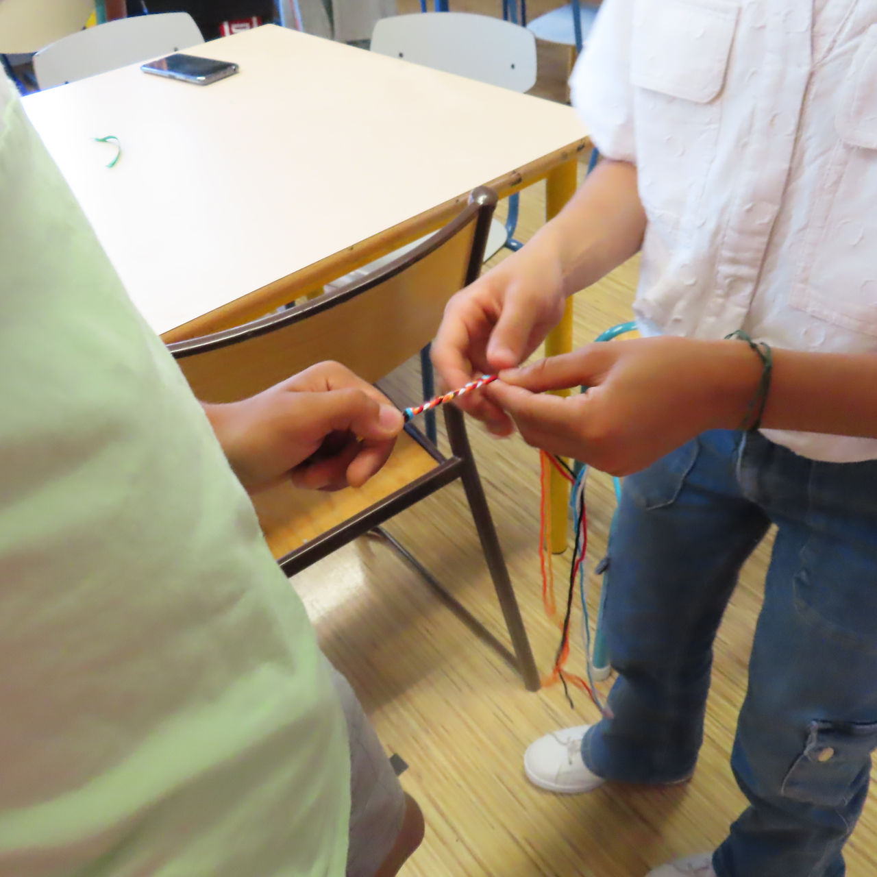 Enfants tressent une ficelle colorée ensemble, sur une table en bois Lovely boys.