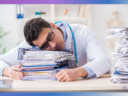 Exhausted healthcare provider with head down on large stack of medical billing paperwork and claims files showing administrative burden and staff burnout