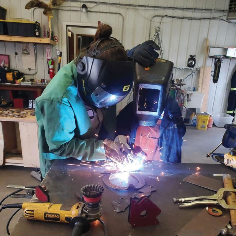 Anne teaching a student welding technique.