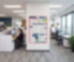 Poster hanging in an office with employees around