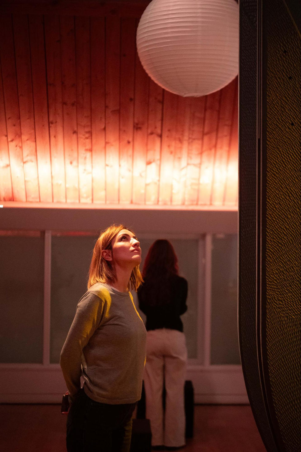 Woman looking up in warmly lit room.