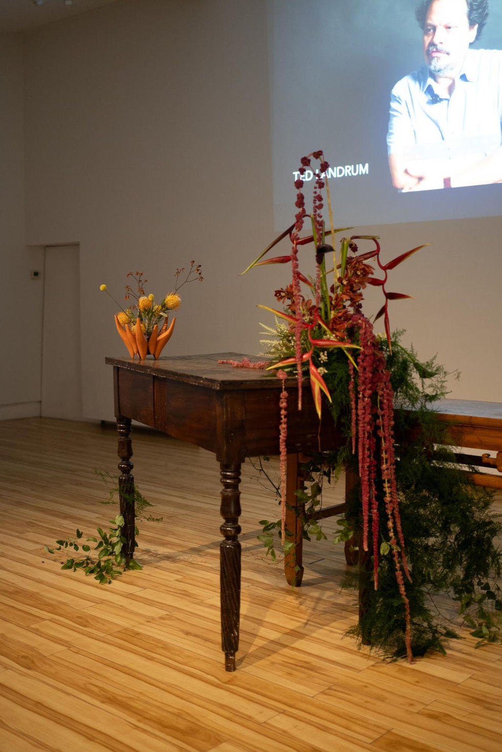 Floral arrangement on wooden table in gallery setting.