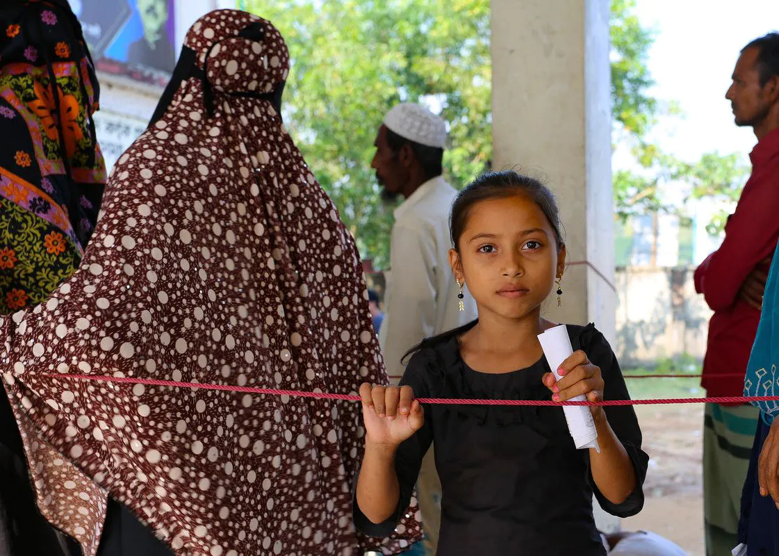 A young girl in a group of people looking at the camera.