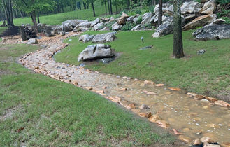 Curved dry creek bed installation managing heavy water runoff from hillside