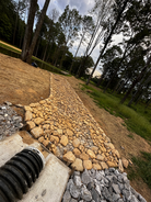 Wide long dry creek bed built to handle heavy water flow from large drainage pipe