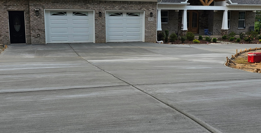 Freshly poured wide curved concrete driveway with two foot paver border edge