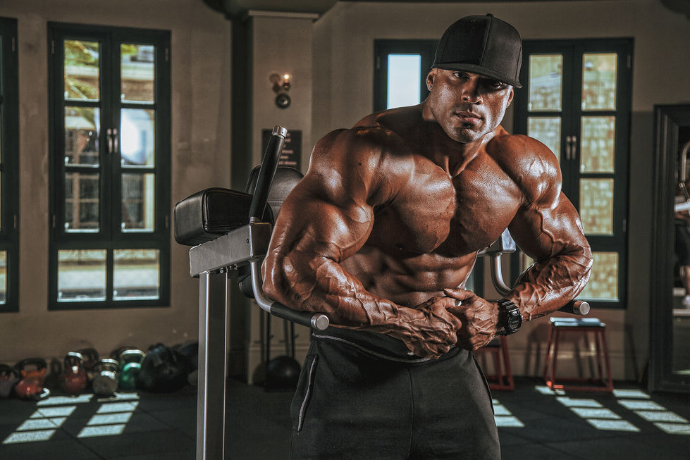 Henri-Pierre Ano ifbb pro Bodybuilder posing in a gym setting.