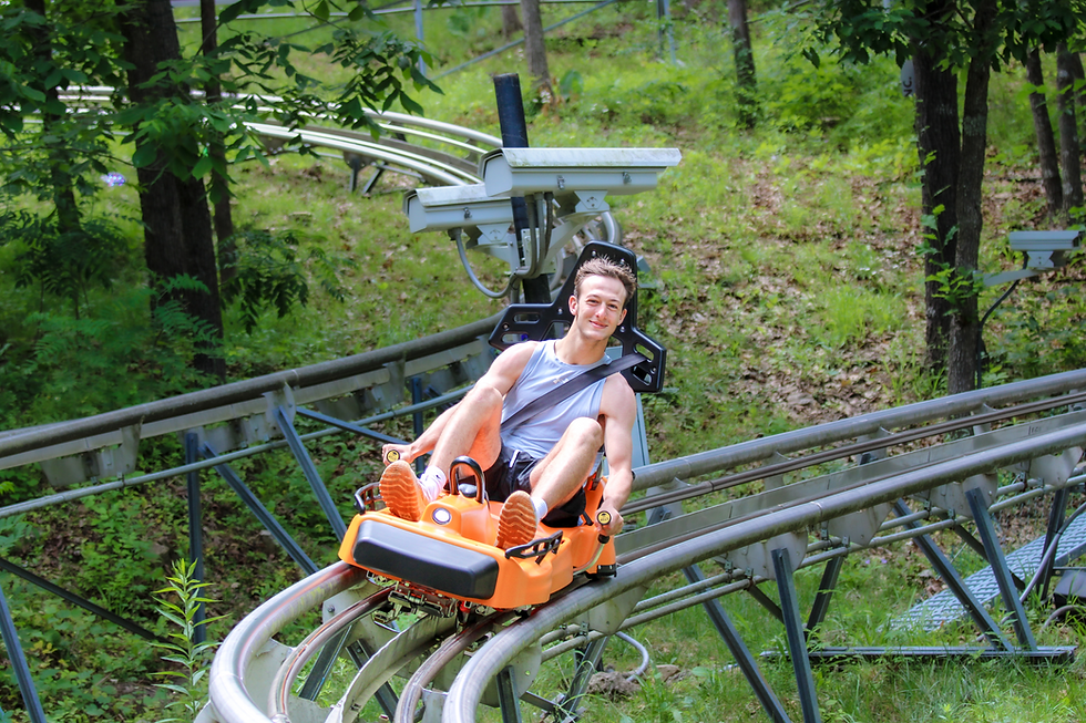 handsome man riding a bright orange sled at The Branson Coaster, surrounded by nature and wildlife