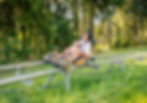 Child and woman happily riding a mountain coaster through a forest. The coaster is orange with "Mountain Coaster" text visible.