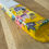 Thumbnail: Yellow painted decorative Mezuzah with colorful village art on wooden table background