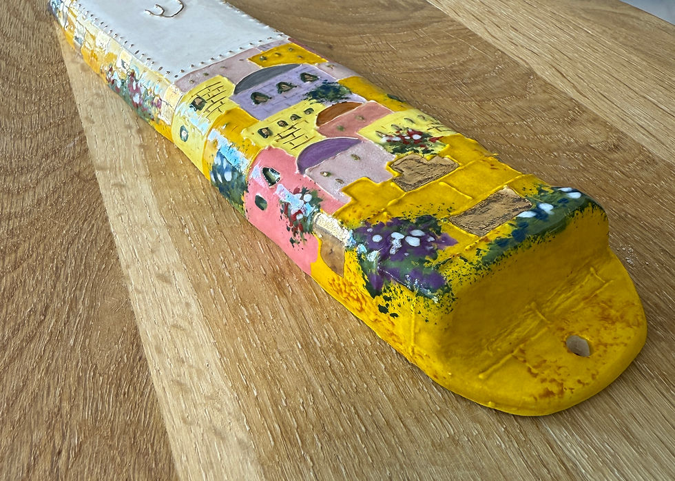 Thumbnail: Yellow painted decorative Mezuzah with colorful village art on wooden table background