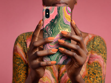 Person holding a print-on-demand phone case with a swirl-patterned case at The Yellow Studio. The background is pink, matching the phone's pink, green, and yellow hues.