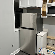 Kitchen reconstruction in progress with appliances temporarily relocated and cabinets being rebuilt — interior restoration work.