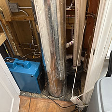 Dark utility closet with water damage behind wall insulation — identifying moisture and mold issues near HVAC or plumbing.
