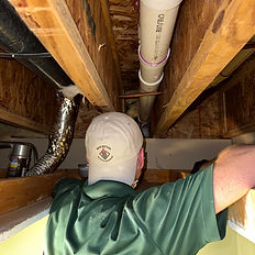 Restoration technician inspecting water line access in basement ceiling — leak source identification during mitigation.