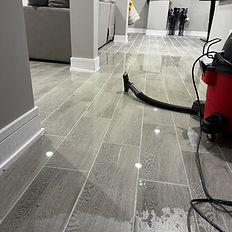 Standing water on tile floor in finished basement with wet vacuum — Rock Bottom Restoration emergency water damage cleanup and extraction in Illinois home.