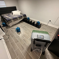 Drying equipment setup in flooded bedroom with tile floors — dehumidifiers and air movers running after water damage.