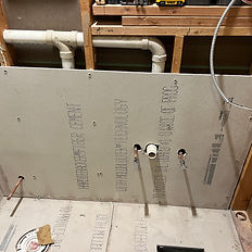 Backer board installation with exposed plumbing and framing — rough-in stage of a bathroom or kitchen reconstruction project.