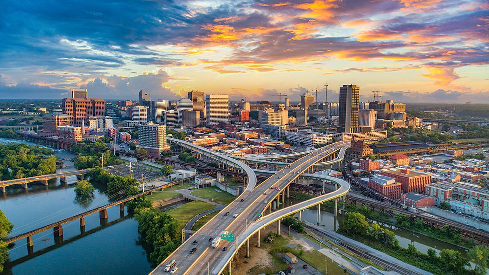 A serene fall scene with a pond, vibrant orange flowers, colorful trees, and a building in the background under a partly cloudy sky.