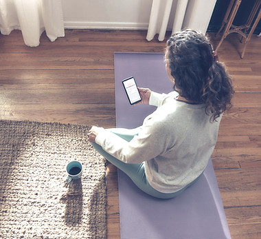 Woman meditating on yoga mat with phone