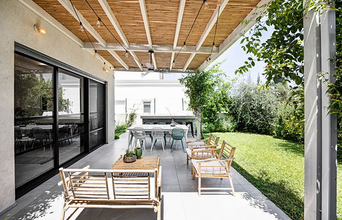 מרפסת בית עם רהיטים, שולחן ודשא ירוק. dikla-pinto