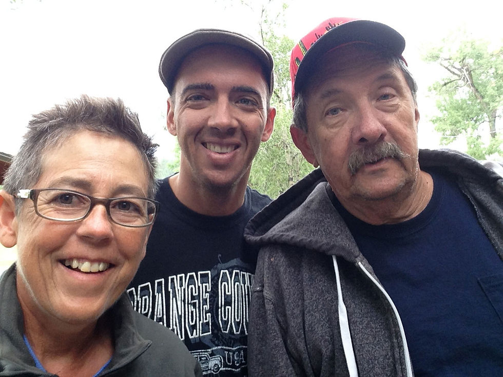 A selfie of a woman with short brown hair and glasses to the left, a young man with a ball cap in the middle, and an older man with a moustache and red ball cap on the right.