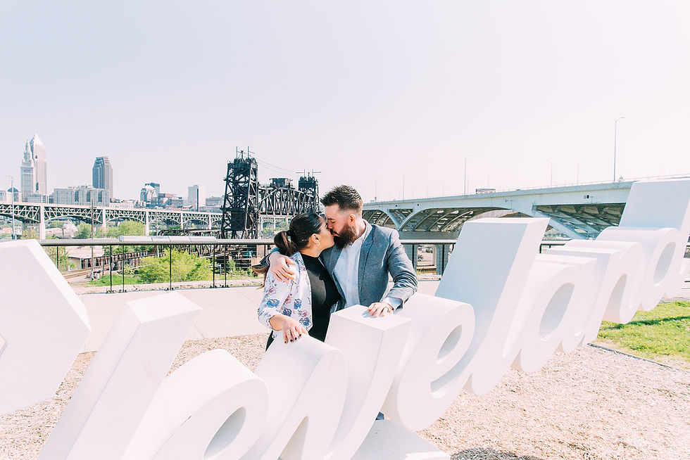 Man and woman kiss right next to the Cleveland script sign