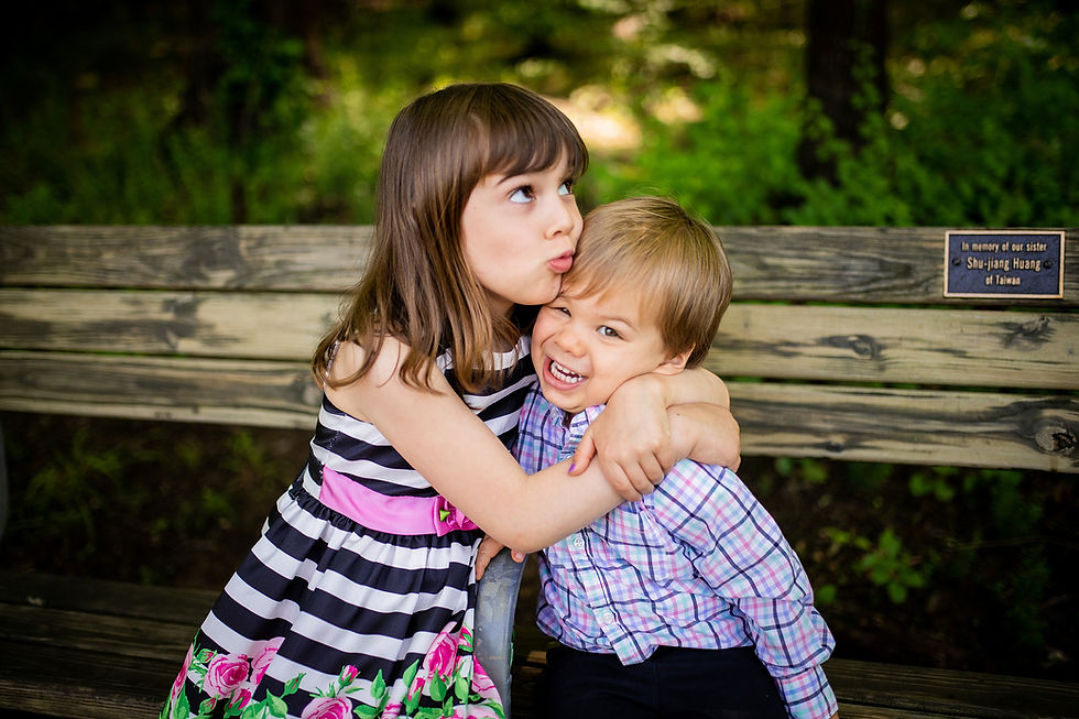 Little girl and boy hug and goof around on a bench in Maryland