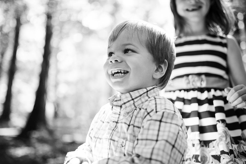 Little boy laughs and giggles as he stands in front of his sister in Maryland.